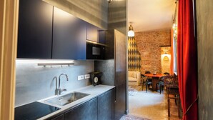 Una cucina moderna con mobili scuri, un lavello in acciaio inossidabile e una sveglia sul piano di lavoro.