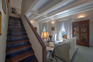 A staircase leading to a living area with a sofa, a lamp, and a cabinet. - Luxury Historic Villa, Heated Jacuzzi, Lemon Garden & Stunning Amalfi Sea Views (Amalfi)