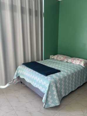 A room with a bed, a green wall, and a window with curtains. - Apartment 05 Manaus (Manaus)