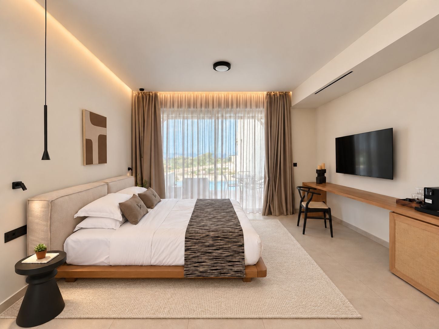 A modern hotel room with a large bed, a desk, a flat-screen TV, and a view of the ocean.