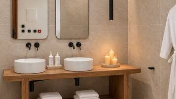 A modern bathroom with two sinks, a mirror, a hanging light, and a towel rack.