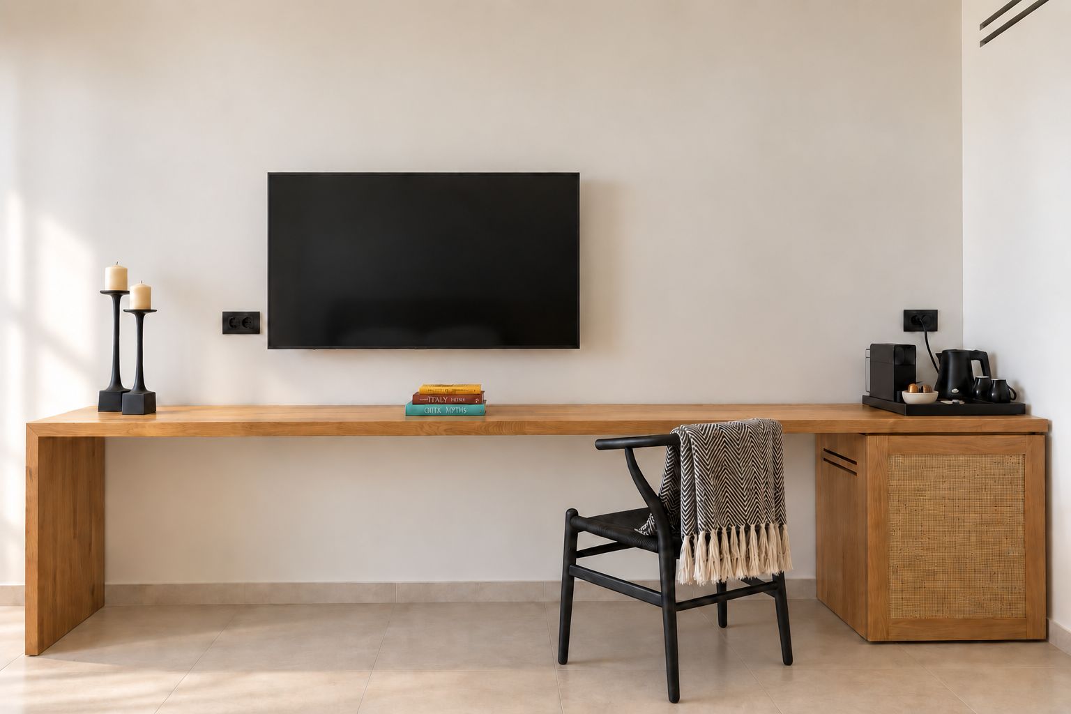 A modern room with a wooden desk, a black chair, a television mounted on the wall, and a small cabinet with a woven basket.