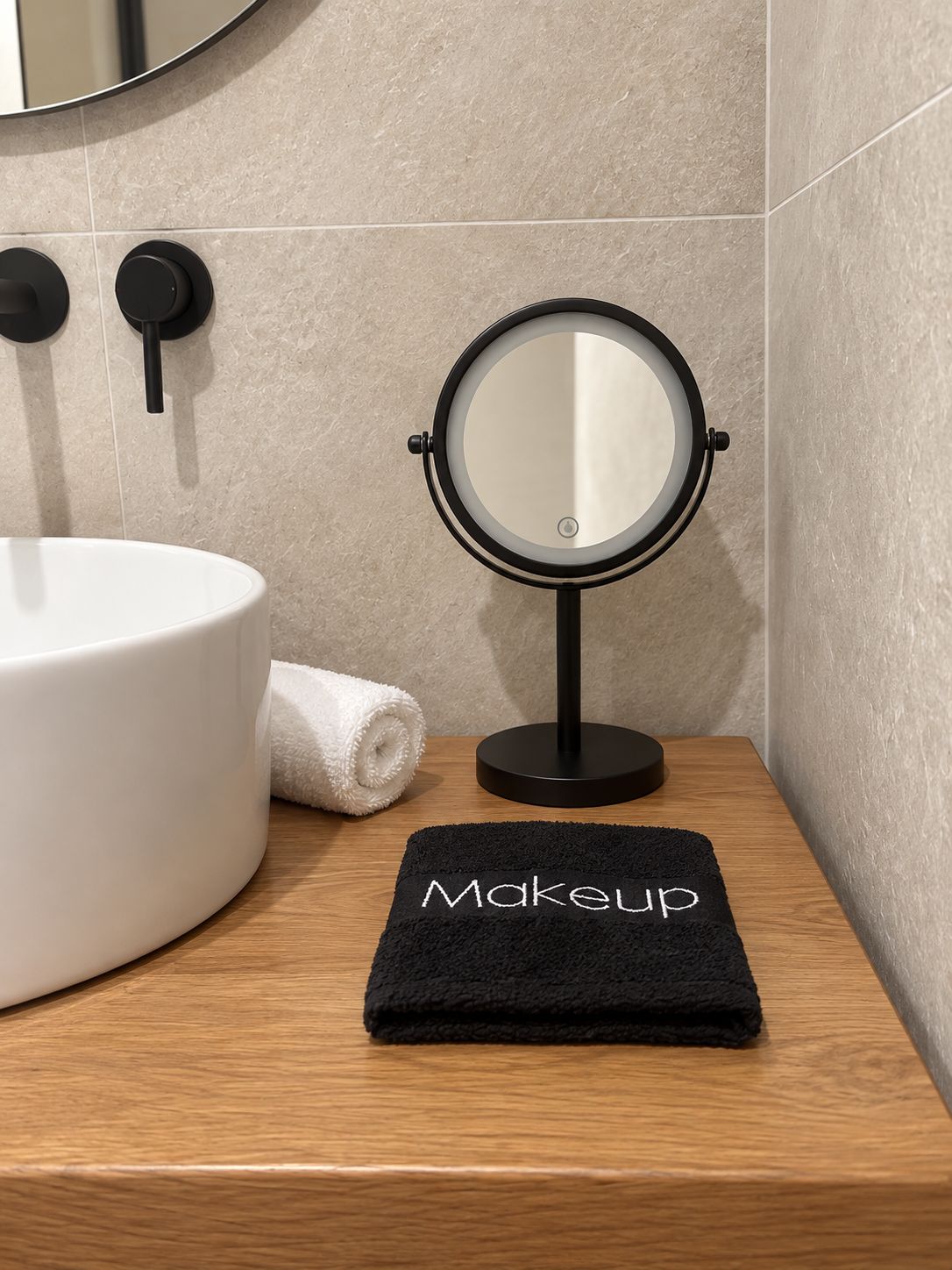 A bathroom vanity with a round mirror, a white sink, and a black towel with 'Makeup' written on it.