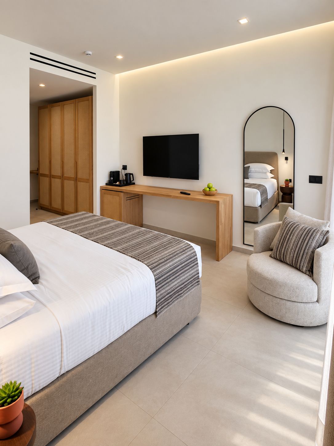 Una habitación de hotel moderna con cama, escritorio, televisor, silla y armario.