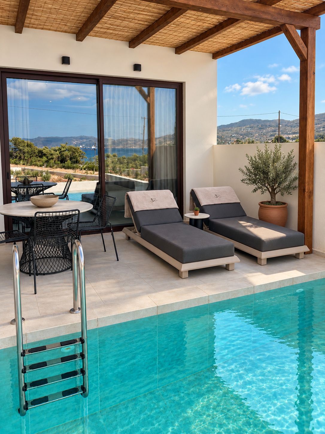 Area piscina con lettini, un tavolo e vista sul mare.