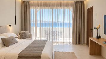 A bedroom with a bed, bedside table, and a view of the sea.