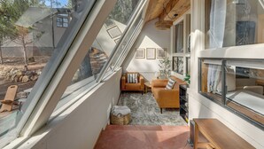 Una habitación acogedora con techo inclinado, ventanas amplias y vistas al exterior.
