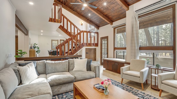 Amplia sala de estar con un sofá modular grande, una mesa de centro de madera y una escalera con barandilla de madera.