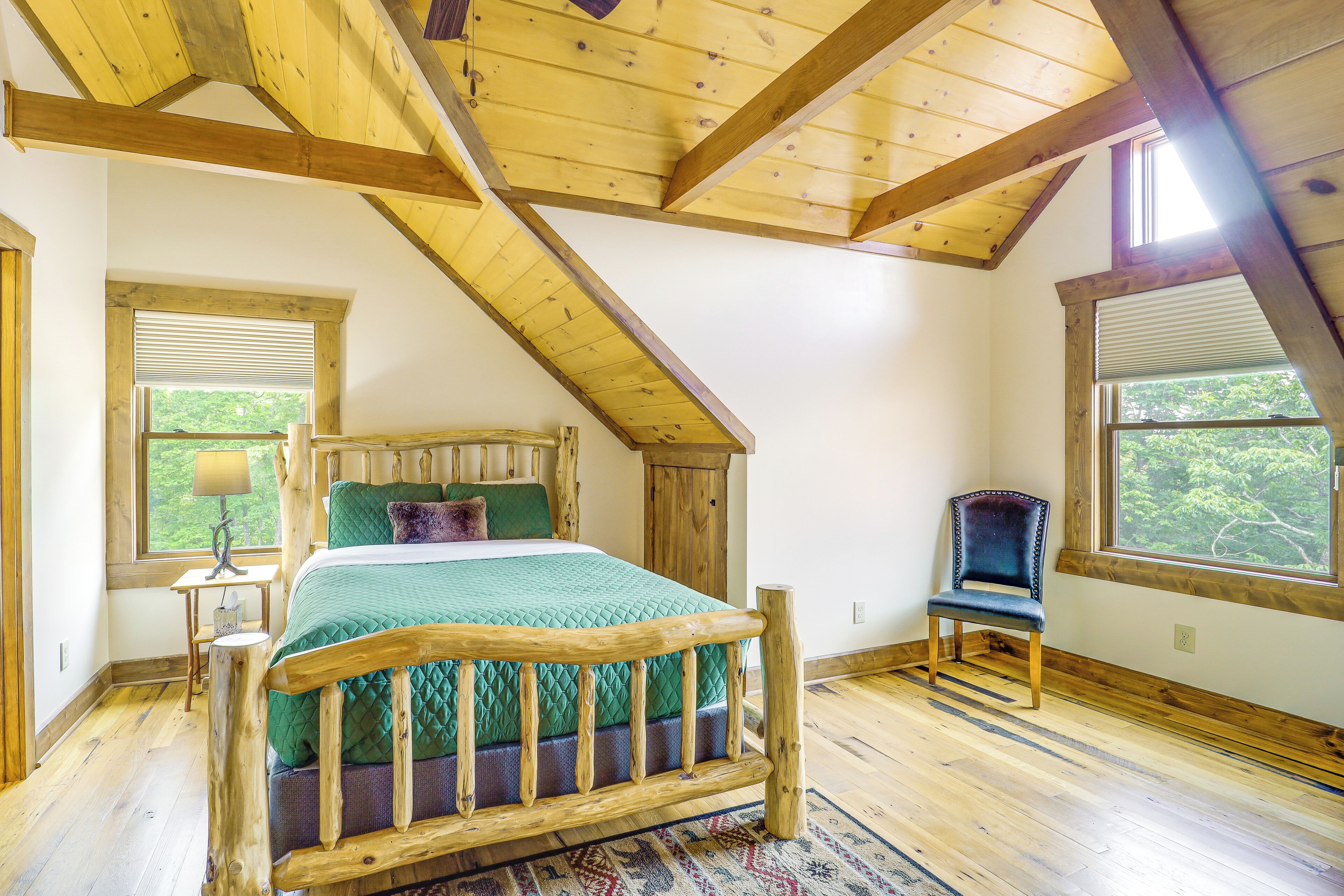 A room with a wooden bed, a chair, a window, and a lamp.