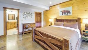 Une chambre avec un lit en bois, un ventilateur de plafond, un panneau mural en bois et un tableau représentant un ours.