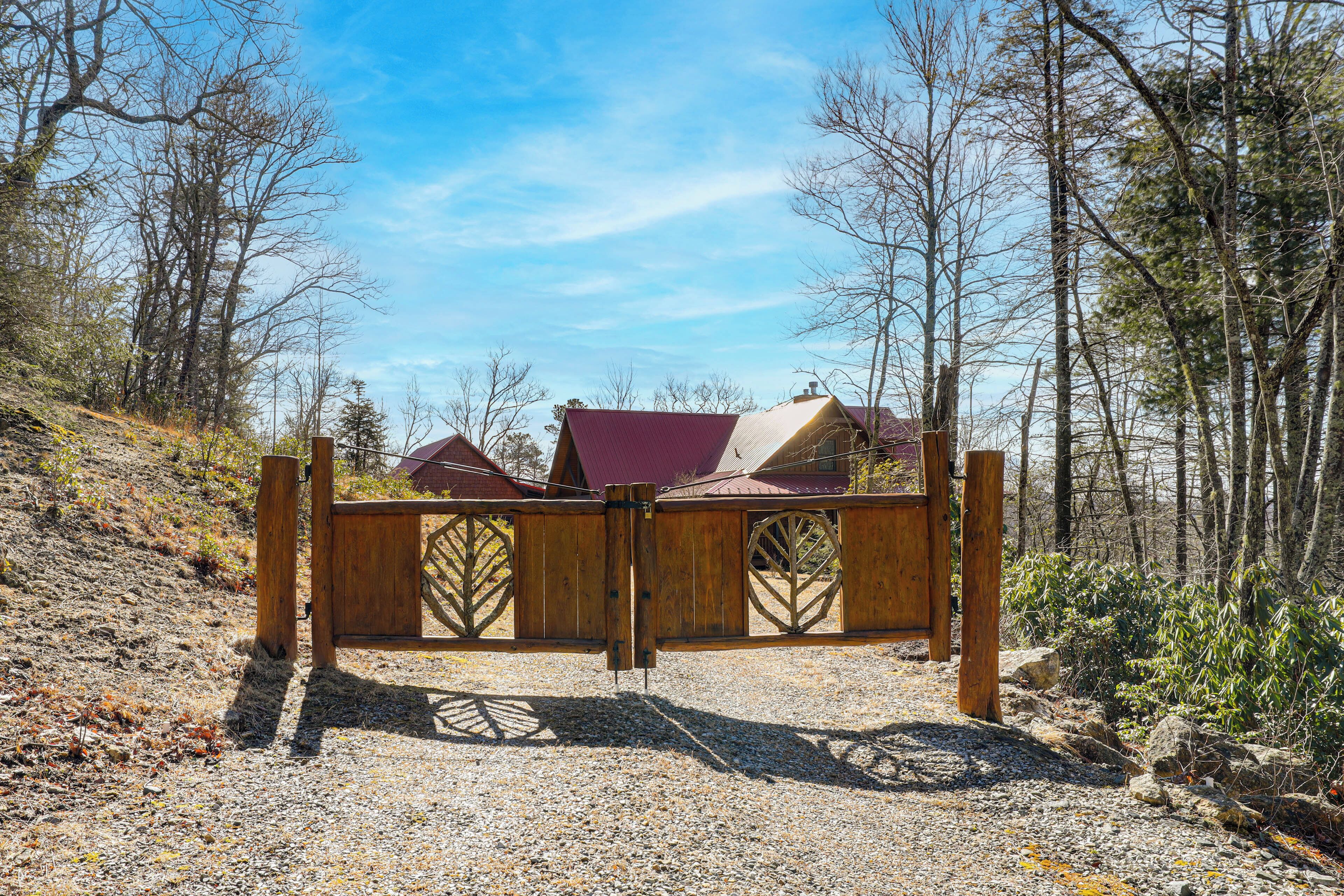 A wooden gate with a metal latch in a forested area.