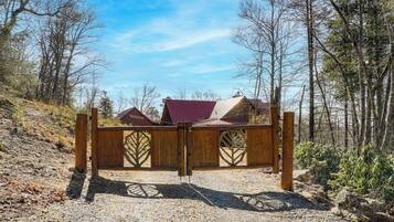 A wooden gate with a metal latch in a forested area.