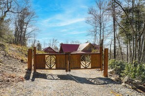 Ein hölzernes Tor mit einem Metallriegel in einem bewaldeten Gebiet.