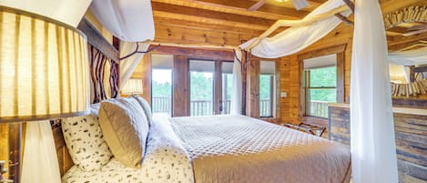 A wooden cabin bedroom with a bed, curtains, and a ceiling fan.