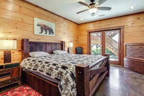 A wooden cabin bedroom with a bed, a ceiling fan, a wooden dresser, and a large window. - Game Room + Deck: Spacious Spruce Pine Retreat! (Spruce Pine)