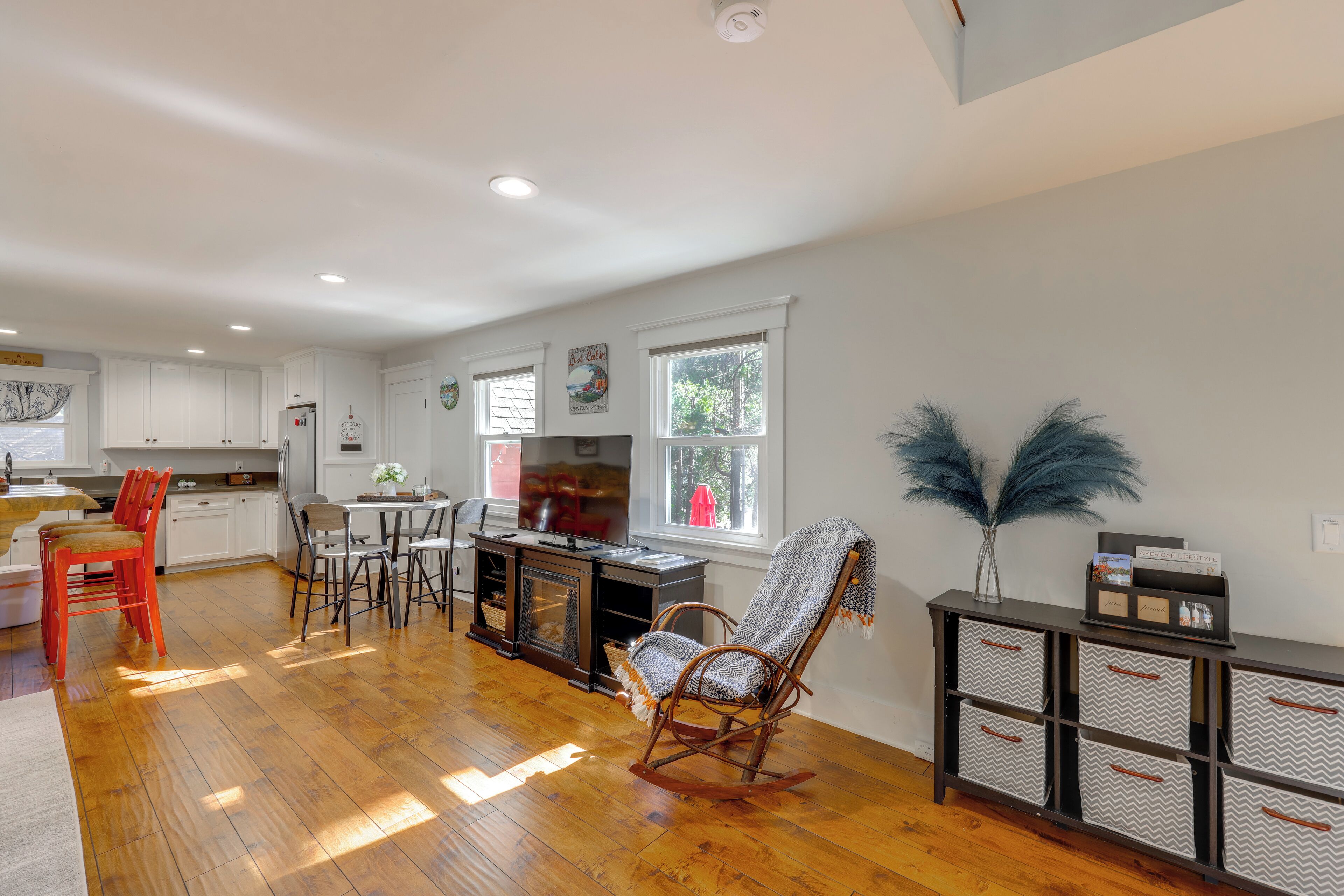 A spacious kitchen with wooden flooring, white cabinets, and a dining area with chairs.