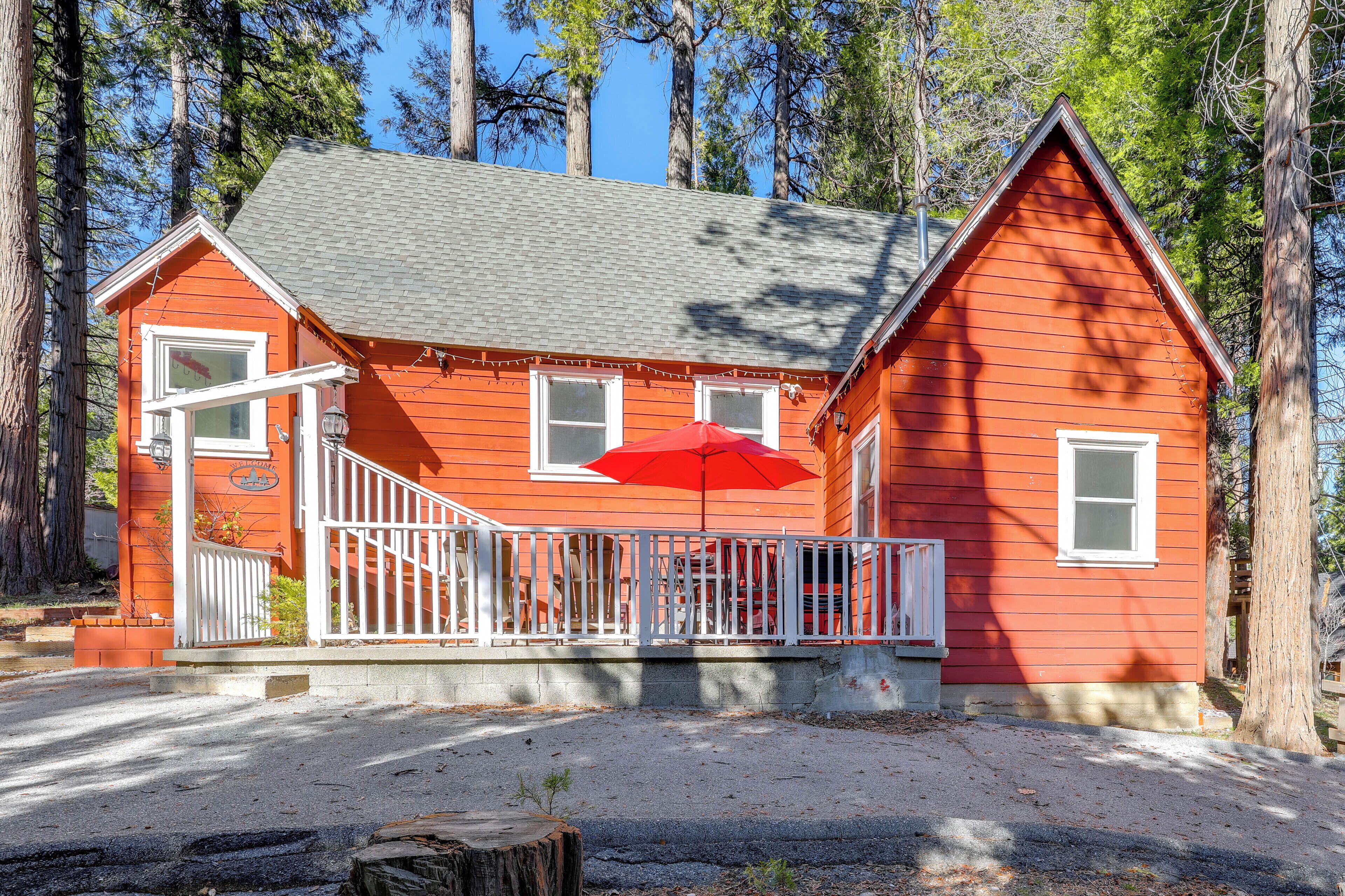 Une cabane en bois rouge avec un porche blanc et un parasol rouge.