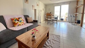 A living room with a sofa, coffee table, and dining area with chairs. - Le Cocon Provençal, T2 Downtown Hyères (Hyères)
