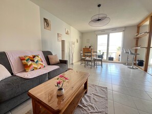 Ein Wohnzimmer mit Sofa, Couchtisch und Essbereich mit Stühlen.