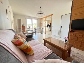 Ein Wohnzimmer mit einer Couch, einem Holztisch und einem Fernseher.