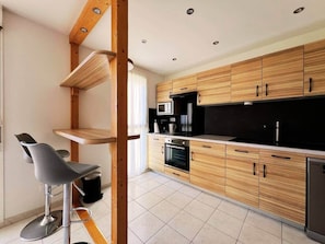 Eine moderne Küche mit Holzschränken, einem eingebauten Backofen und einer schwarzen Arbeitsplatte.