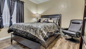 A bedroom with a bed, a chair, and a lamp.