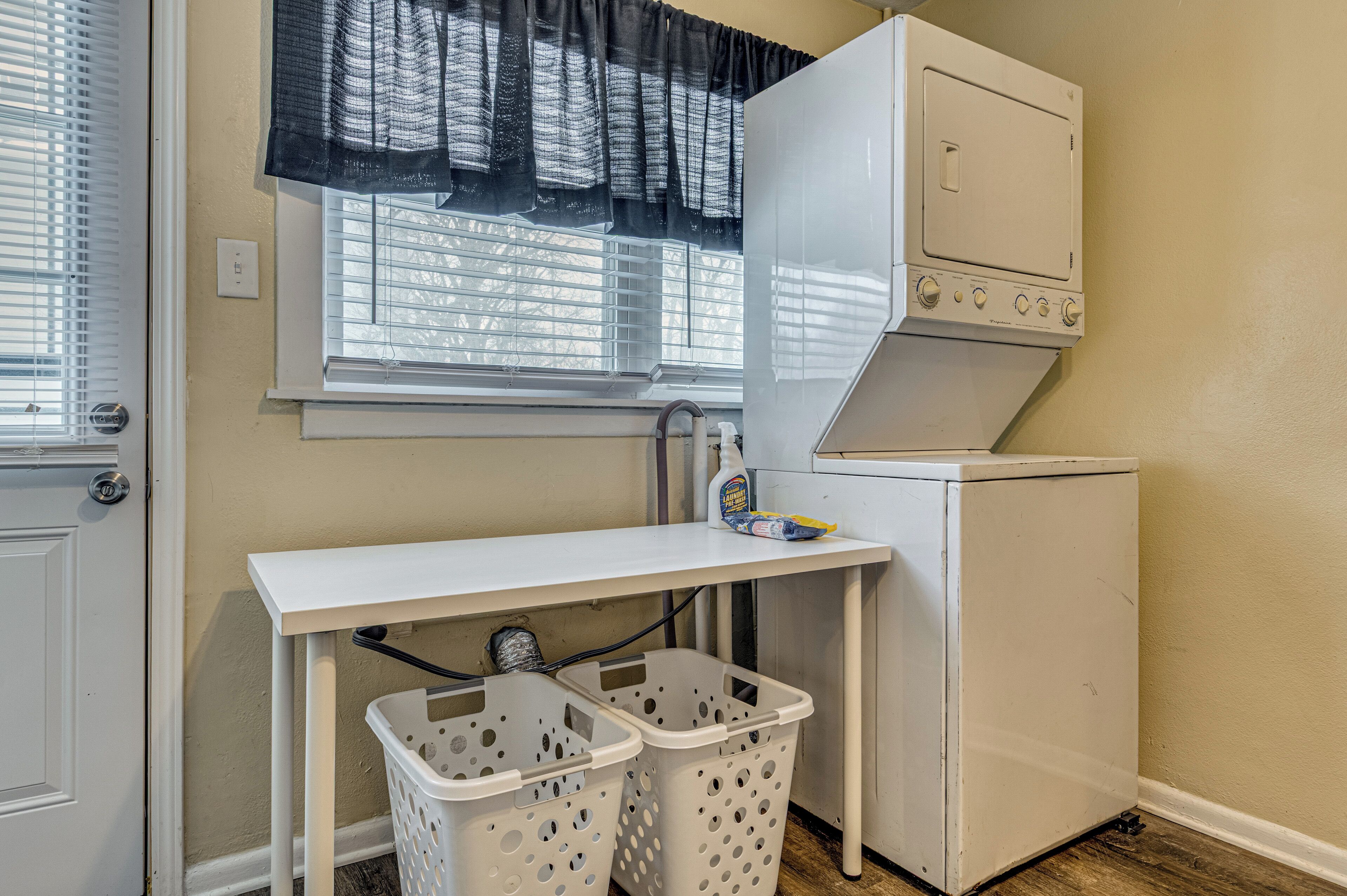 A laundry room with a washing machine, a dryer, a table, and two baskets.