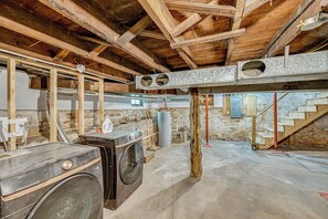 Una sala de bugaderia amb rentadores, un escalfador d'aigua gran i un sostre de fusta.