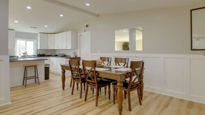 A modern kitchen with white cabinets, a wooden dining table, and six chairs. - Mountain Retreat in Commerce w/ Billiards + Darts (Commerce)