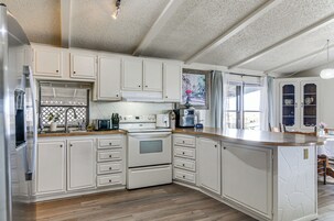 Una cocina con muebles blancos, horno empotrado y una isla grande con acabado similar a la piedra.