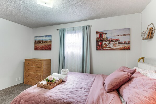 Una camera da letto con un letto, una cassettiera e due quadri appesi al muro.