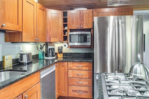 A kitchen with wooden cabinets, a stainless steel refrigerator, a microwave, a gas stove, and a dishwasher.