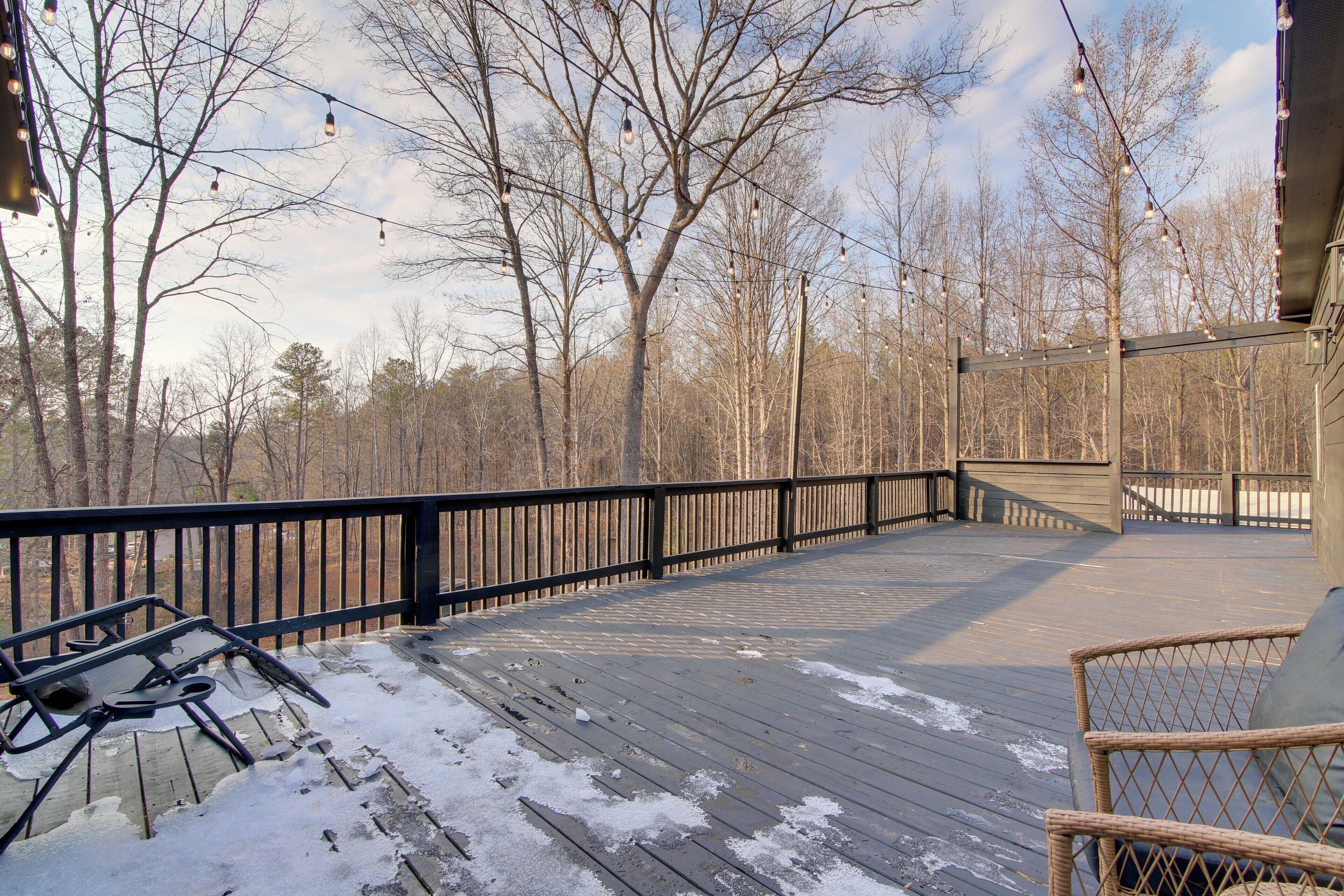 A wooden deck with a black railing, a wicker chair, and a table.