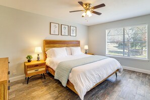 A bedroom with a wooden bed, two bedside tables with lamps, a ceiling fan, and a window with blinds. - Lakeside Retreat: Large Spacious Home w/ Game Room (Kemp)