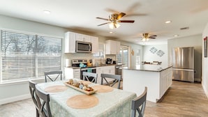 A modern kitchen with white cabinets, a central island, and a ceiling fan. - Lakeside Retreat: Large Spacious Home w/ Game Room (Kemp)