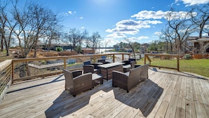 A wooden deck with wicker furniture and a view of a residential area. - Lakeside Retreat: Large Spacious Home w/ Game Room (Kemp)
