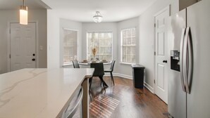 A modern kitchen with a marble countertop, a dining table with chairs, and a refrigerator. - Walk to the Greenline: Sleek Cordova Home w/ Patio (Cordova)