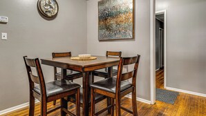 Un comedor con una mesa y sillas de madera, un reloj de pared y un cuadro abstracto grande.