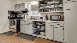 Una cocina moderna con armarios blancos, electrodomésticos de acero inoxidable y un ventanal que proporciona luz natural.