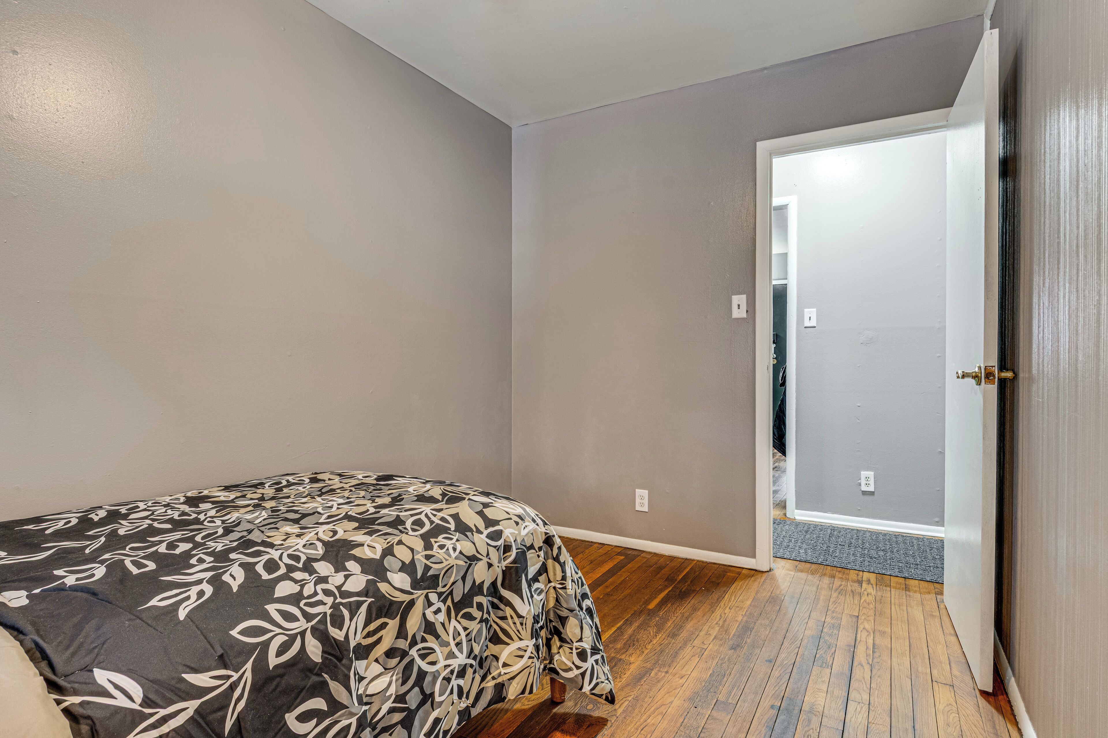 Een slaapkamer met een bed, een deur en een houten vloer.