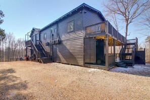 A two-story building with a covered outdoor area, a staircase, and a gravel driveway. - Woodsy North Georgia Mountain Hideaway w/ Fire Pit (Commerce)