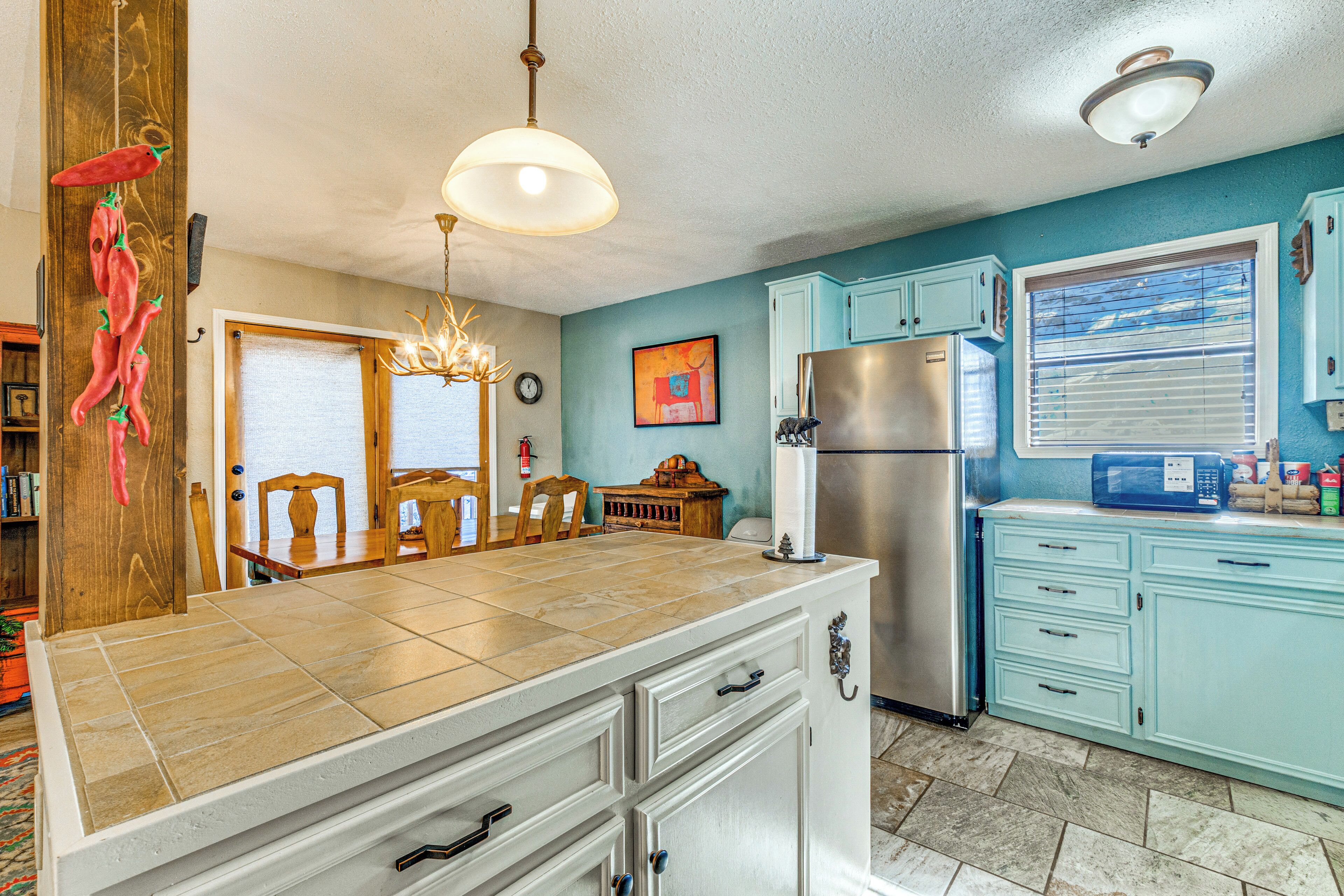 A kitchen with a large island, a refrigerator, and a microwave.