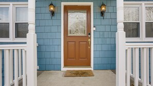 A front door with a brown glass panel, white trim, and a doormat.