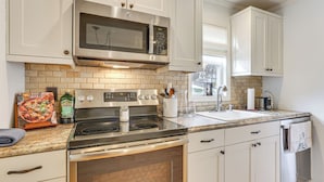 A modern kitchen with white cabinets, a stainless steel microwave, a double oven, and a granite countertop.