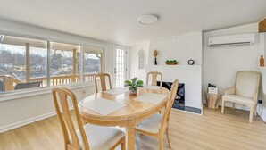 A dining area with a round wooden table, four chairs, a potted plant, and a white brick fireplace. - Herrington Lake Home w/ Deck: Golf, Boat & Relax! (Danville)