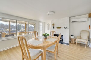 Comedor con una mesa redonda de madera, cuatro sillas, una planta en maceta y una chimenea de ladrillo blanco.