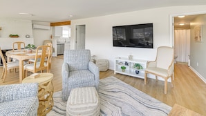 A modern living room with a dining area, a TV mounted on the wall, and a kitchen in the background. - Herrington Lake Home w/ Deck: Golf, Boat & Relax! (Danville)