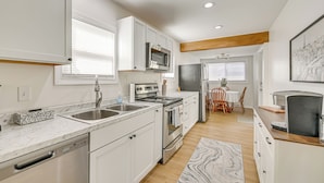 A modern kitchen with white cabinets, stainless steel appliances, and a marble countertop. - Herrington Lake Home w/ Deck: Golf, Boat & Relax! (Danville)