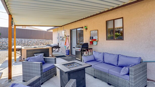 Un patio al aire libre con mobiliario de mimbre, una parrilla y un hogar para fuego.