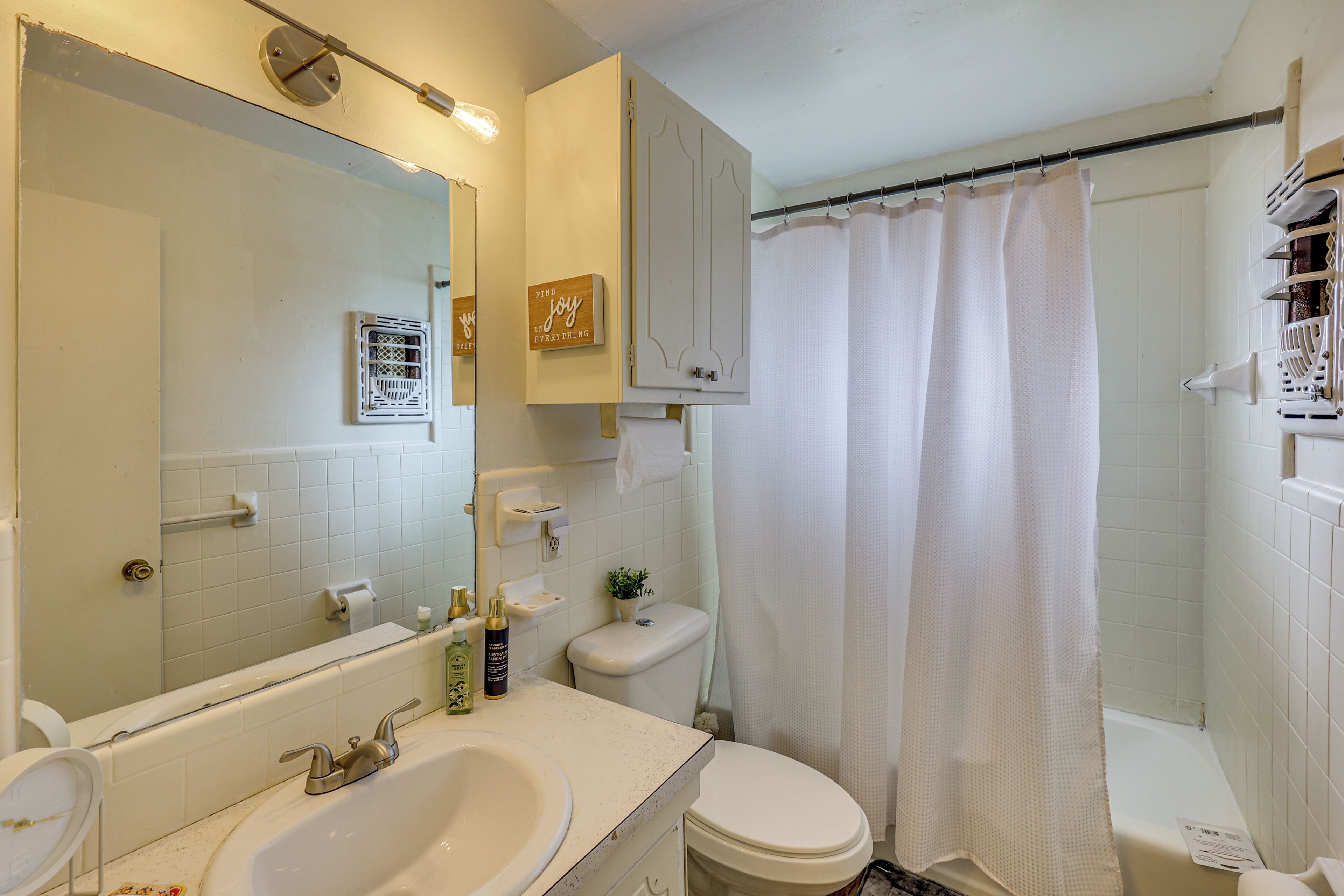 A bathroom with a sink, toilet, and shower curtain.
